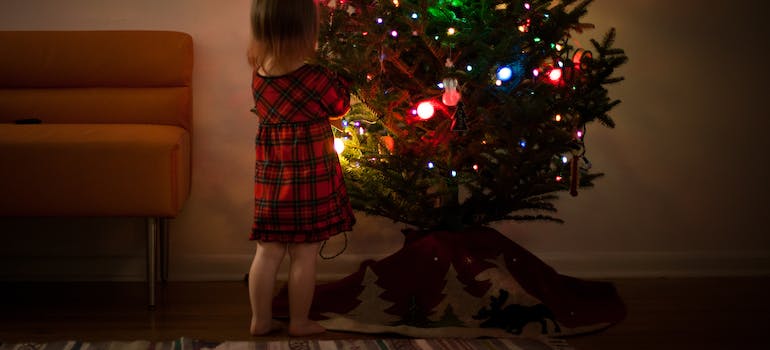 a child standing next to the Christmas tree