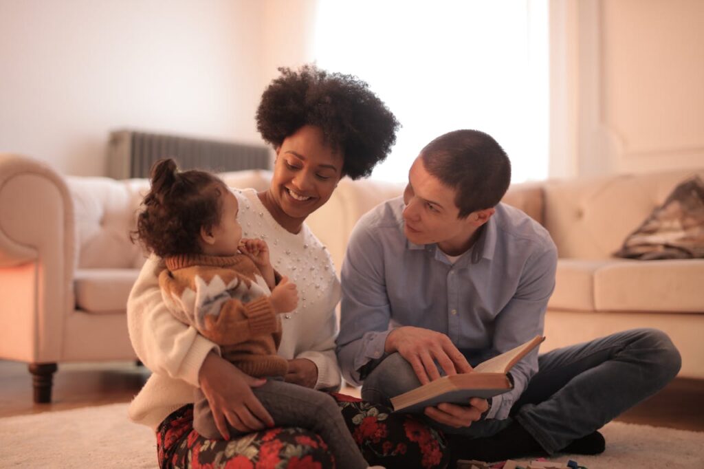 A woman holding a child and a man reading, trying to integrate new partners into a co-parenting setup
